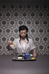 Woman using pencils as chopsticks to enjoy meal of office supplies