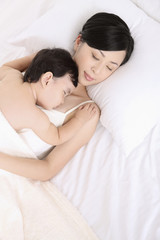 Woman and baby girl asleep on bed