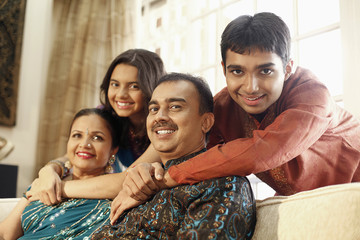 Young man and teenage girl hugging their parents from the back