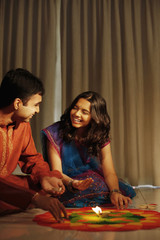 Teenage girl and young man drawing kolam on the floor