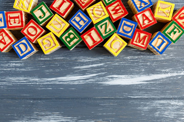 Multicolored wooden cubes with letters on gray background. Set for studying alphabet. Education, back to school concept. Top view, copy space	