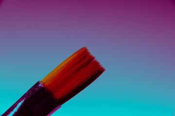 paintbrush and red paint on blue