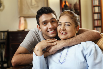 Man posing with his arms around senior woman's neck