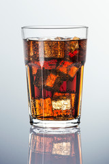 Cold carbonated drink over ice cubes in a  glass