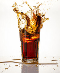 Cold carbonated drink splashing over the glass