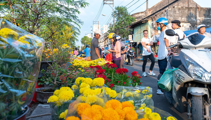 Obraz premium Bustle buying flowers at flower market along street, locals buy flowers for decoration house on Lunar New Year in Ho Chi Minh City, Vietnam.