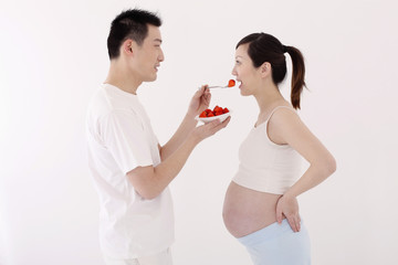 Man feeding pregnant woman strawberries