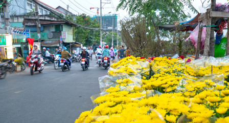Obraz premium Bustle buying flowers at flower market along street, locals buy flowers for decoration house on Lunar New Year in Ho Chi Minh City, Vietnam.