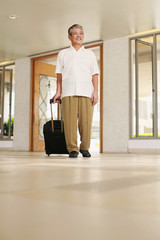 Man walking into hotel lobby with his suitcase