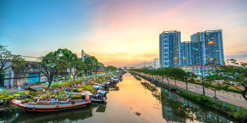 Fototapeta na wymiar Flower boats full of flowers parked along canal wharf in sunset, a place for bustling flower market trade lunar new year in Ho Chi Minh City, Vietnam