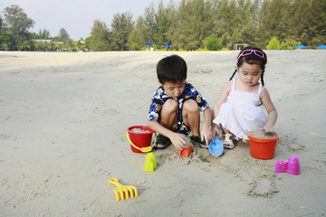 Boy and girl playing with sand on the beach