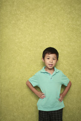 Boy standing at the wall with his arms akimbo