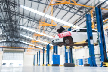 Blurred images of electric lifts for cars in service, placed on the epoxy floor in the car factory service. Background of automobile repair service center for industry
