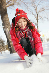 Woman in warm clothing making snowball