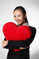 Businesswoman hugging a heart-shaped cushion