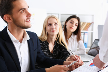 Group of people hold silver pen ready to make