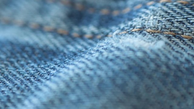 Macro detail of blue jeans sliding to the side.