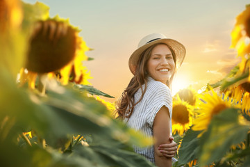 Beautiful young woman in sunflower field at sunset