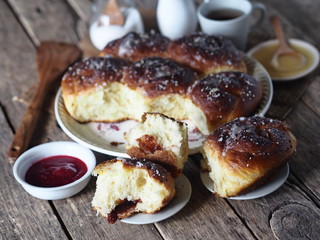 Homemade cake.Buns with jam filling, sprinkled with sesame and icing sugar, on an ancient wooden background, with ingredients and a Cup of tea