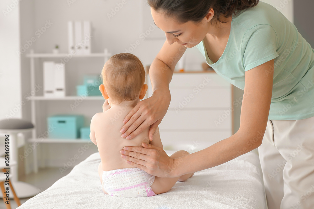 Wall mural massage therapist working with cute baby in medical center