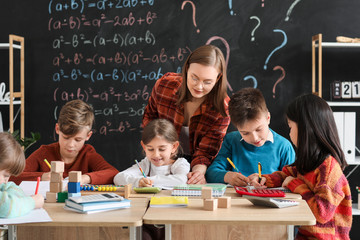 Children with math teacher during lesson in classroom - obrazy, fototapety, plakaty