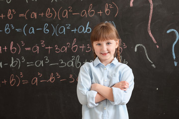 Little girl near school blackboard in classroom