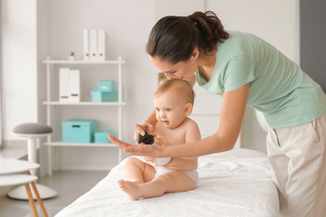 Massage therapist working with cute baby in medical center