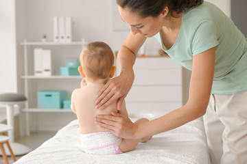Massage therapist working with cute baby in medical center