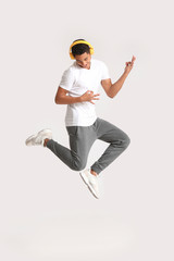 African-American teenager dancing and listening to music against light background