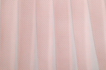 Pleased pink tulle, photographed close-up. Background for the texture of outerwear and fashion.