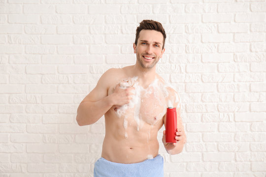Handsome man taking shower against white background