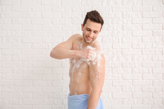 Handsome man taking shower against white background