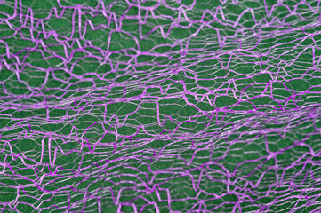 Guipure lying on a colored cloth, photographed close-up. Background for the texture of outerwear and fashion.