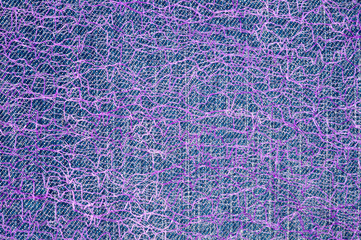 Guipure lying on a colored cloth, photographed close-up. Background for the texture of outerwear and fashion.