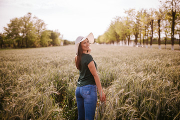 A beautiful attractive smiling caucasian woman with a straw hat in a field of grain