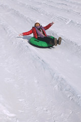 Woman sliding down snowy hill on inner tube