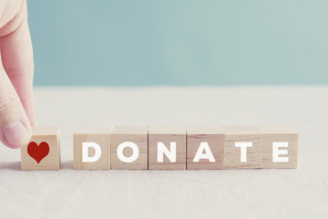 Hand holding red heart wooden blocks with word DONATE