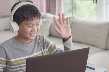 Preteen tween teen Asian boy making facetime video calling with laptop at home, using zoom  online virtual class , homeschooling,learning remotely 