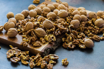 Shelled and shelled walnuts on a wooden board on the table. Healthy nutrition, vegetarianism, diet.