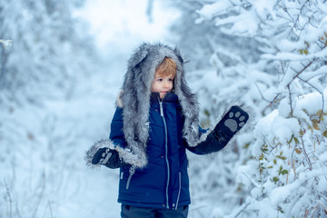 Winter portrait of happy cute child. Childhood on countryside. Funny kid coming to the winter forest on snow landscape.