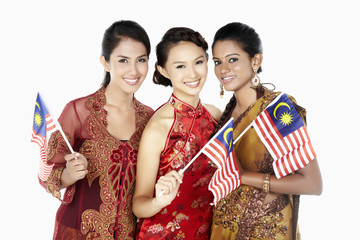 Happy women in traditional clothing holding Malaysian flags