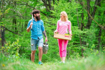 Fototapeta premium Couple of farmers walking in agricultural field. Summer farming. Farmars couple enjoy spring nature and take care about her plants. Two people gardening in the backyard garden.