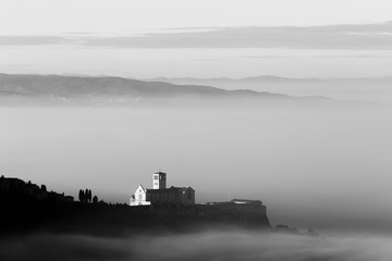 An epic view of St.Francis church in Assisi town (Umbria) above a sea of fog at dawn