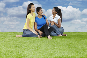 Three young women sitting on the grass, chatting