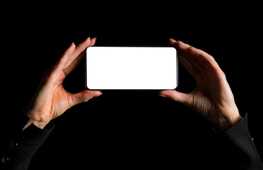 Person holding in hands mobile phone with blank screen and taking photo, image isolated on black...