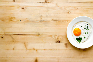 Fried eggs on plate - light wooden dinner table from above copy space