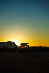Camper cars on beach at sunset