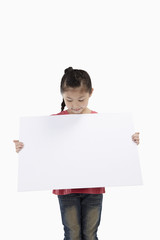 Girl holding blank placard, looking down