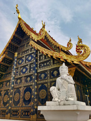 Naklejka premium Buddhist religious art, decorated and gilded facade of a temple and white statue. 