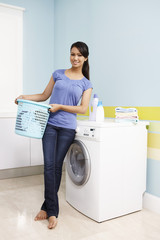 Woman with laundry basket standing next to washing machine
